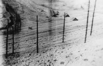 Srpski logor; dvostruka žica, nešto daščara. Vidi se fizijska kobilica za vrata koja su bila nasuprot. Ova vidljiva na slici, vodila su lijevo preko zidića prema Furnaži, u jame (talij. snimak, septembar, 1941).